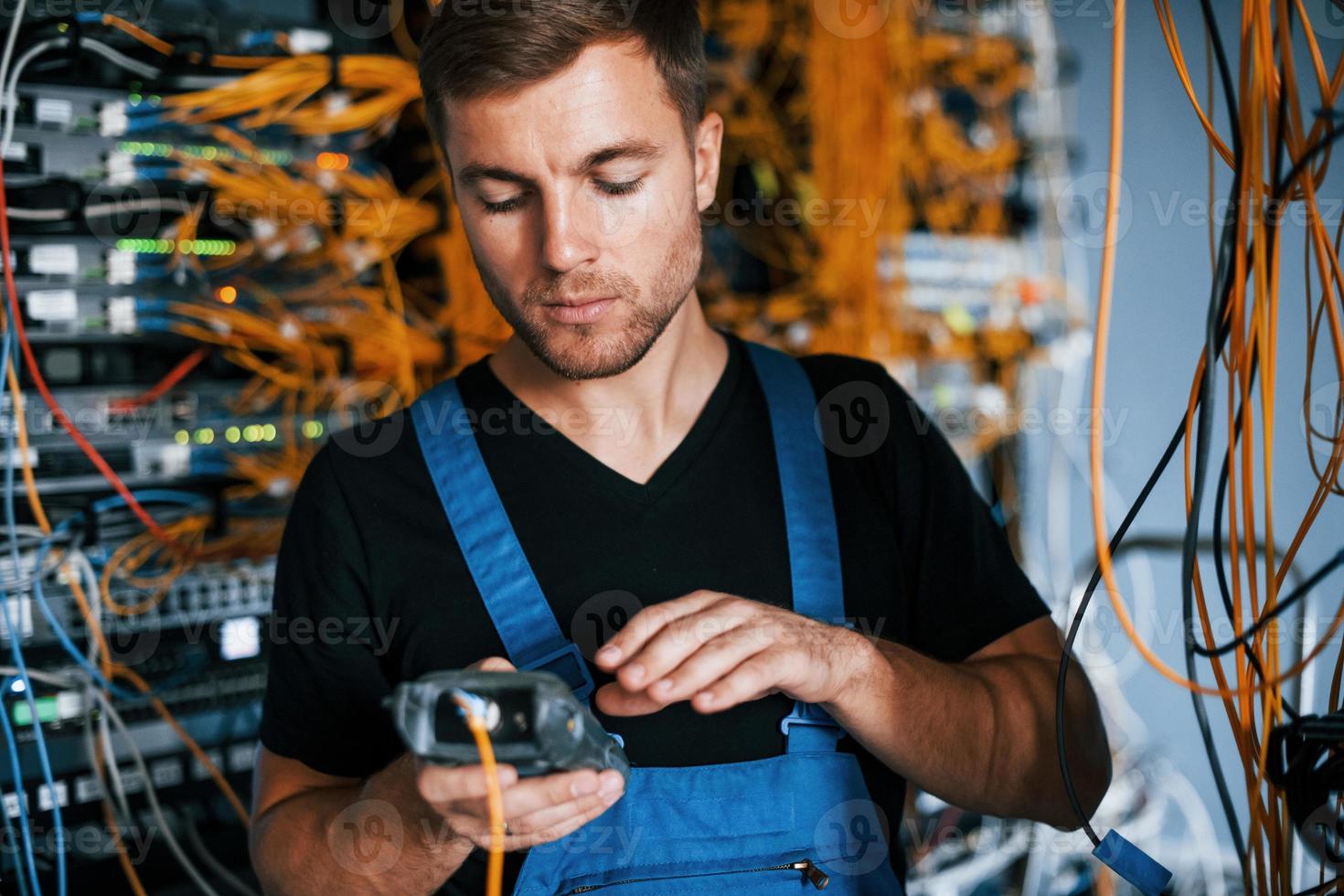 Young man in uniform have a job with internet equipment and wires in server room photo