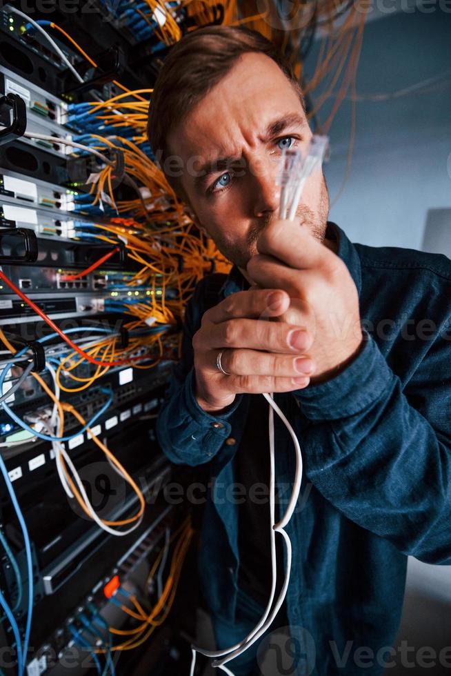 Close up view of funny man with internet wires in server room photo