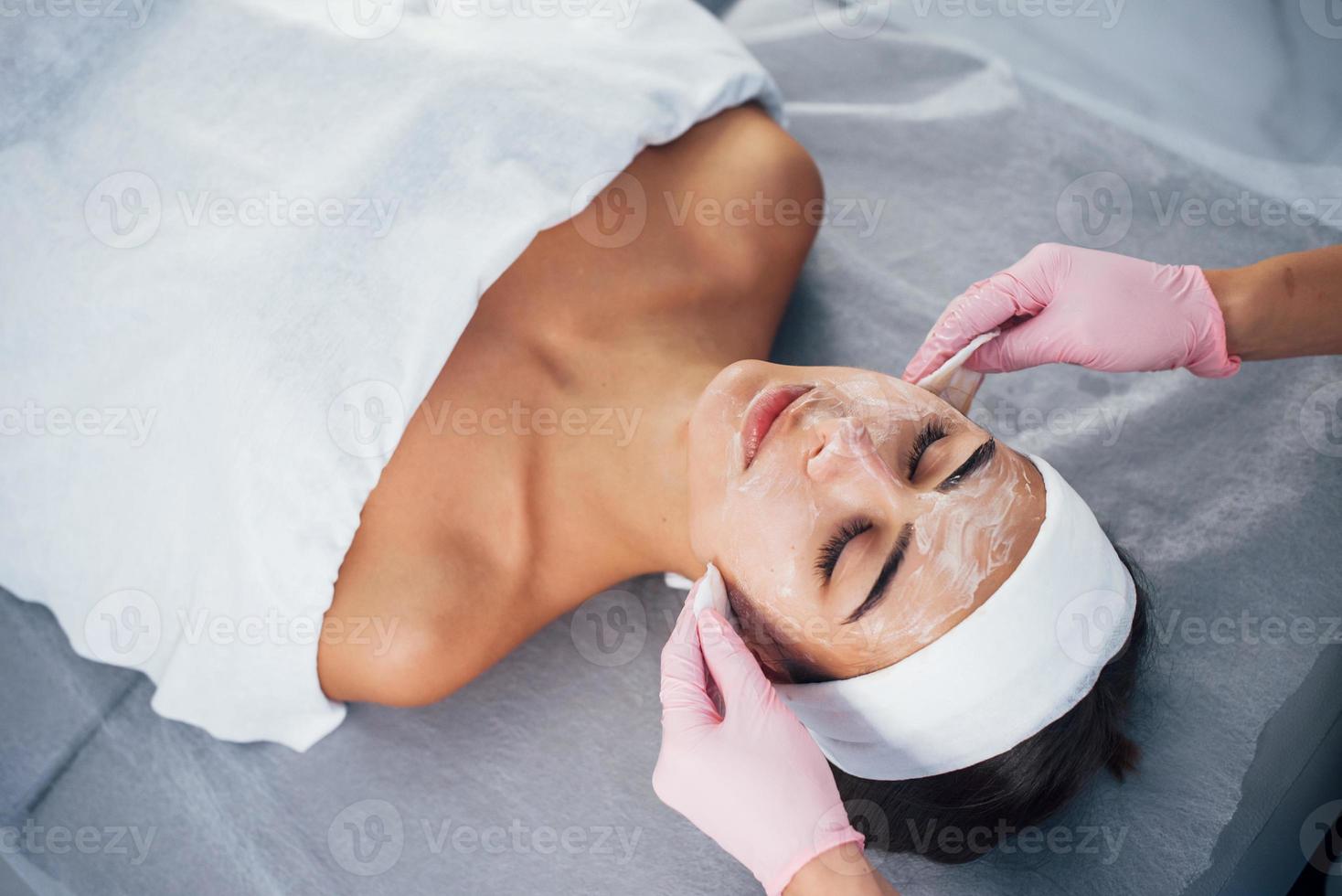 vista de cerca de la mujer que se acuesta en el salón de spa y tiene un procedimiento de limpieza facial foto
