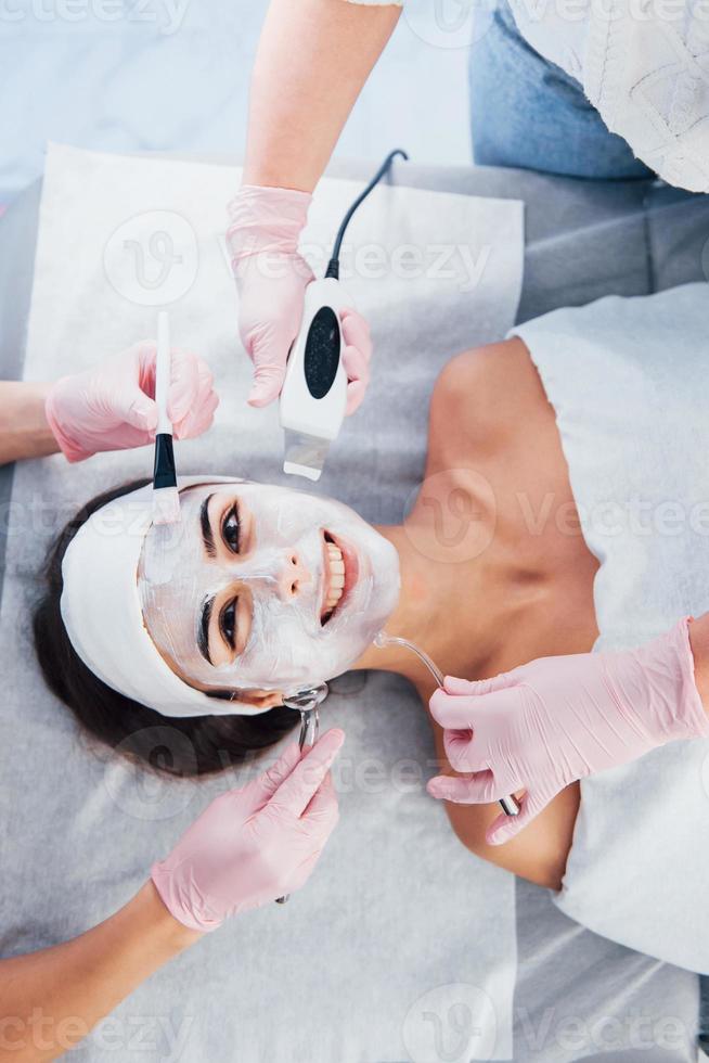 Close up view of woman that lying down in spa salon and have face cleaning procedure by different devices and mask photo