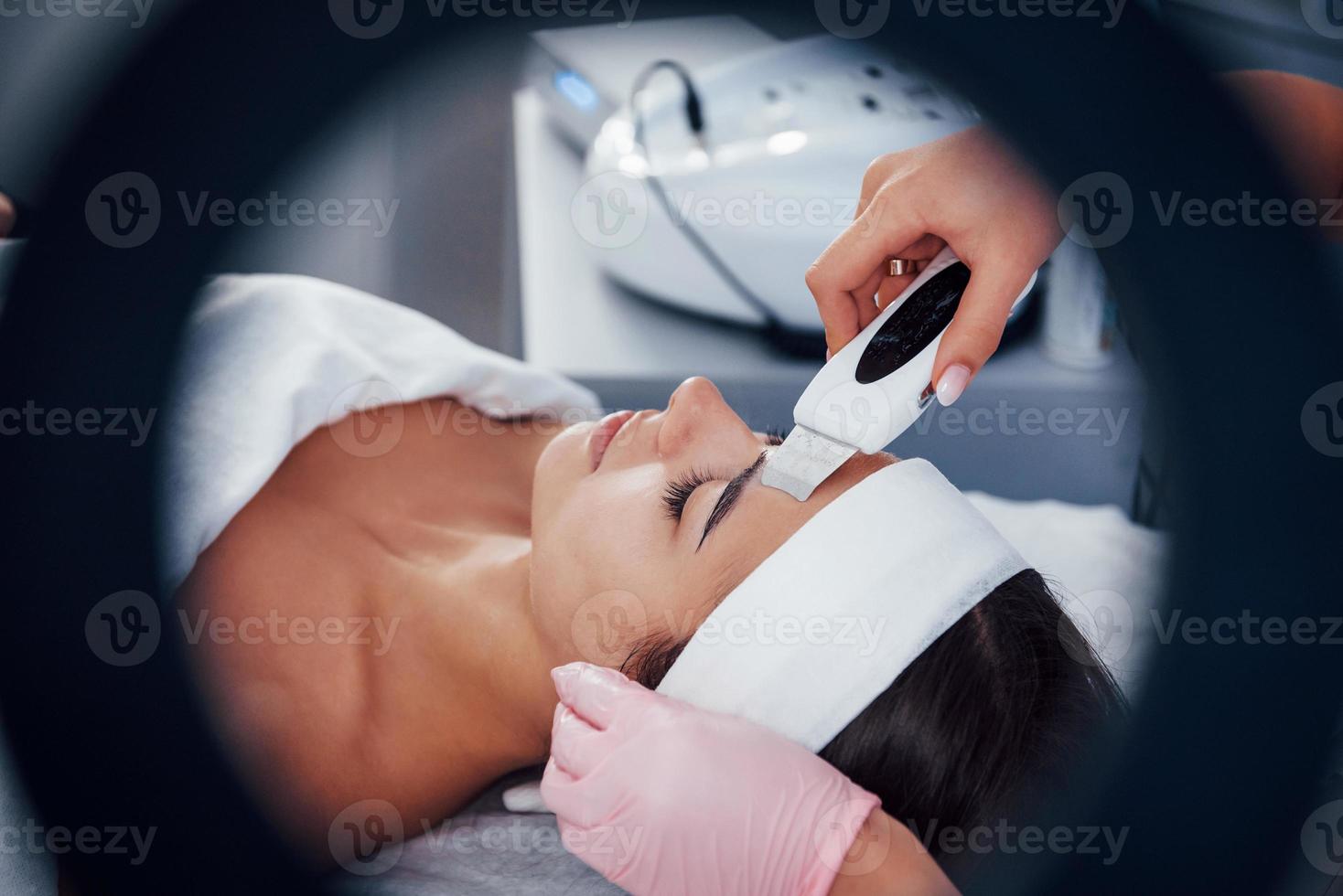 Using special device. Close up view of woman that lying down in spa salon and have face cleaning procedure photo