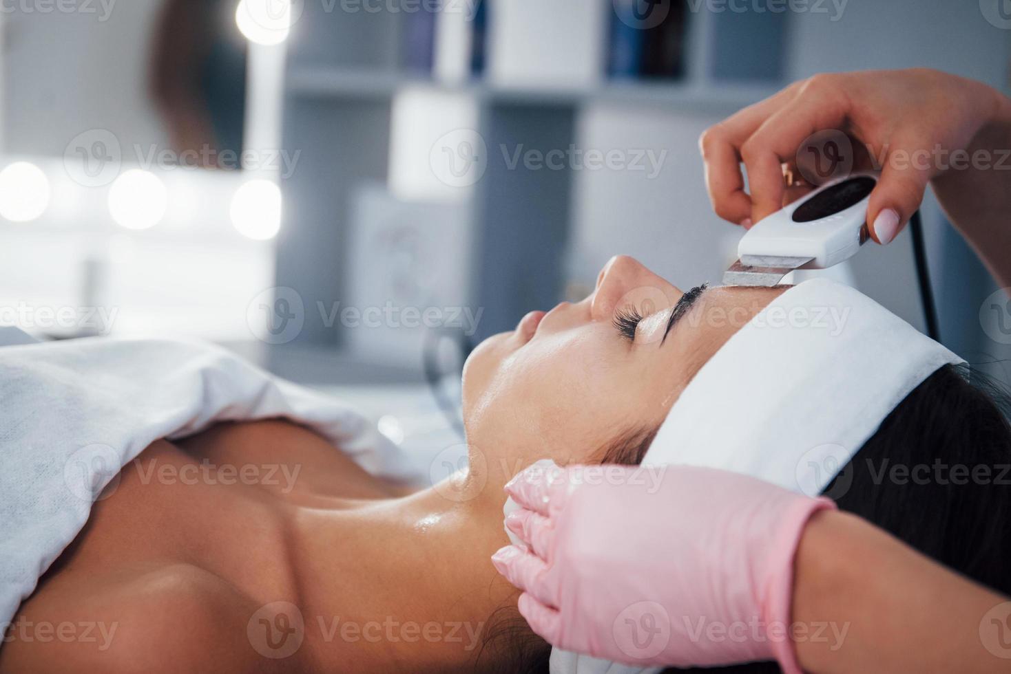 Using special device. Close up view of woman that lying down in spa salon and have face cleaning procedure photo