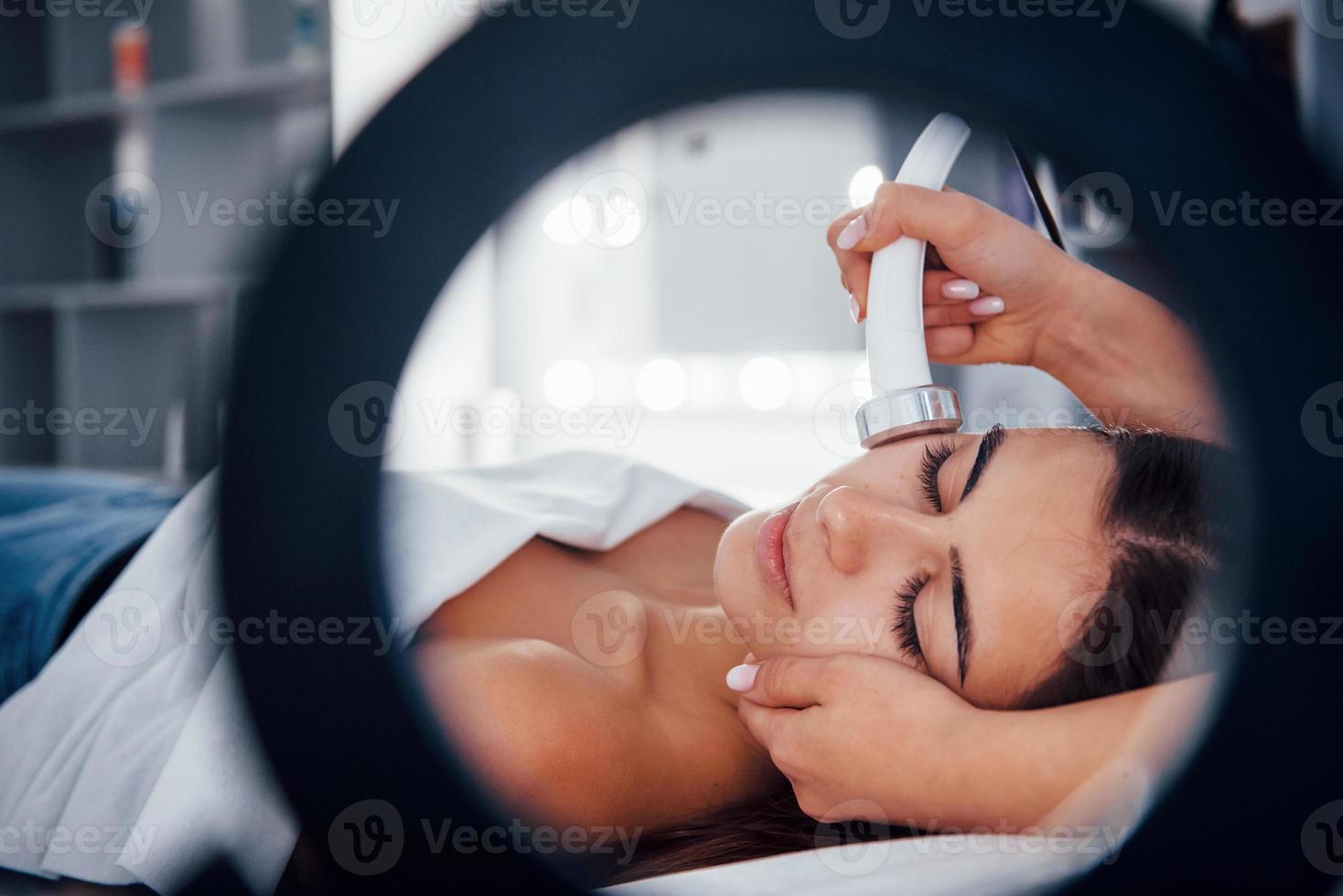 vista de cerca de la mujer que se acuesta en el salón de spa y tiene un procedimiento de limpieza facial foto