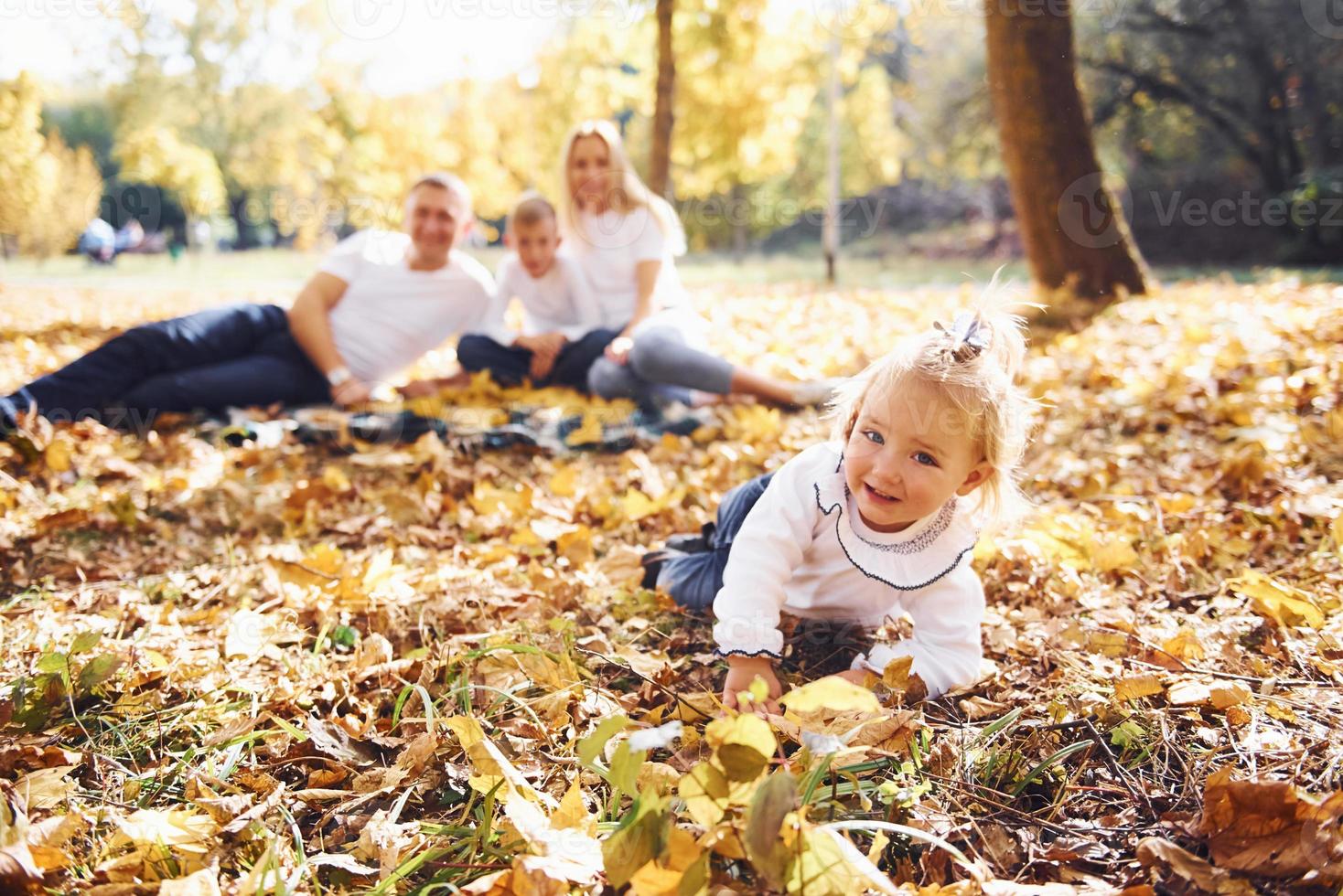 alegre familia joven tumbada en el suelo y descansando juntos en un parque de otoño foto