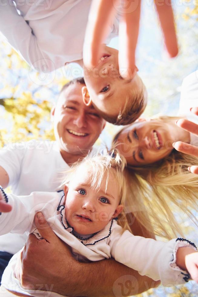 Happy family in autumn park looks down into the camera photo