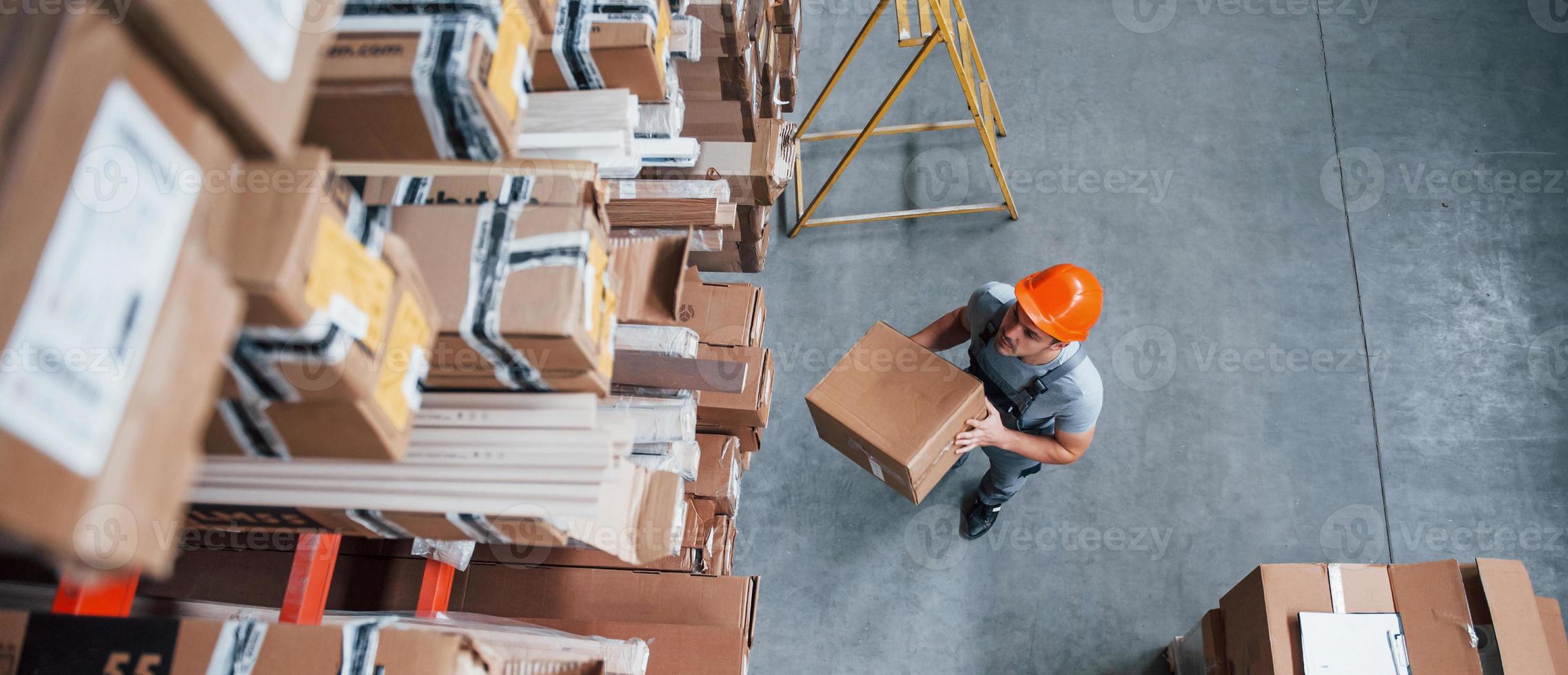 Top view of male worker in warehouse with box in hands photo