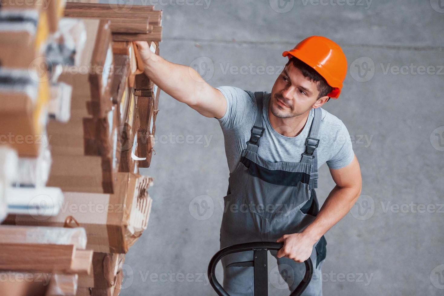 Young male worker in uniform is in the warehouse with pallet truck photo