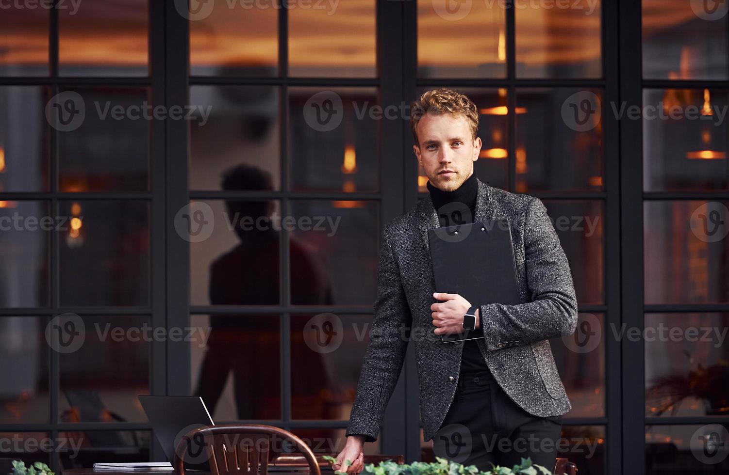 Man in elegant formal wear outside against modern building photo