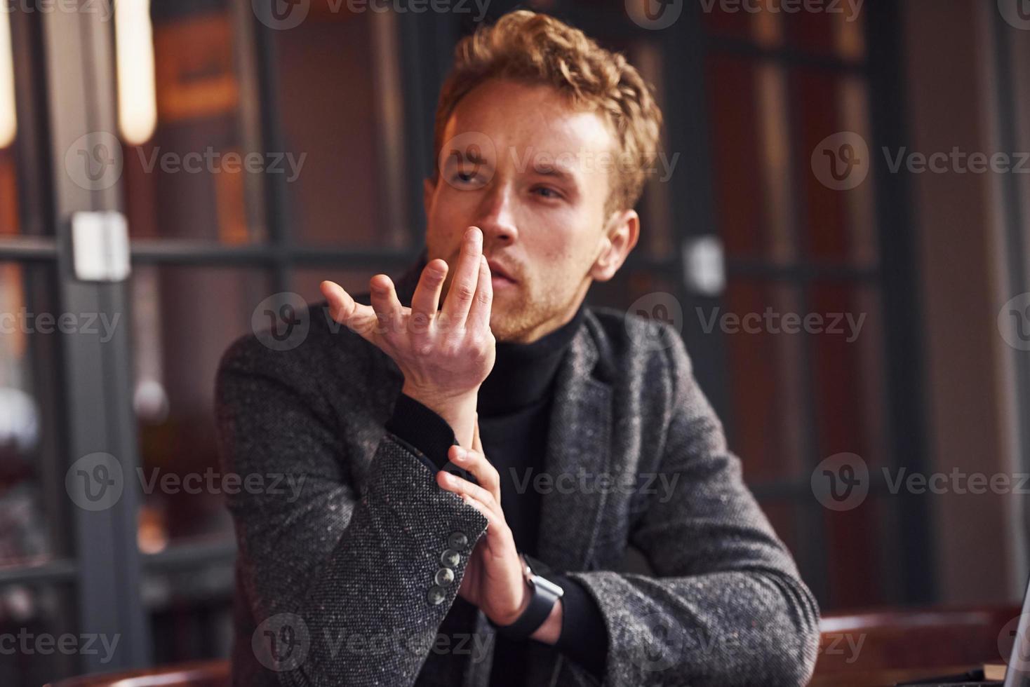Portrait of modern young guy in formal clothes that sits in the cafe photo