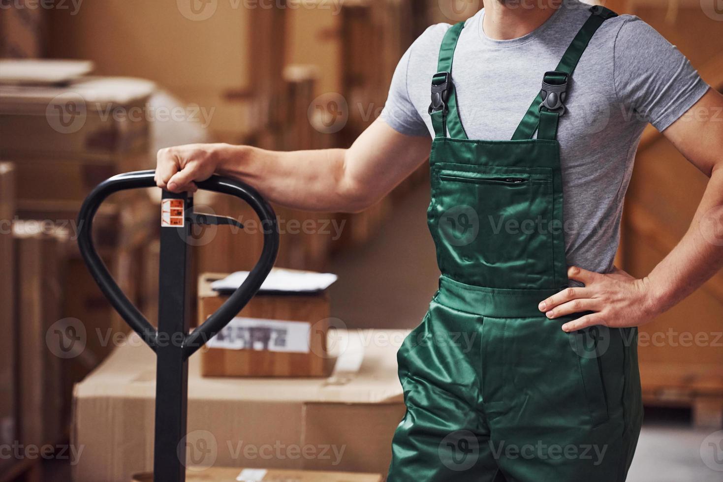 Young male worker in uniform is in the warehouse with pallet truck photo