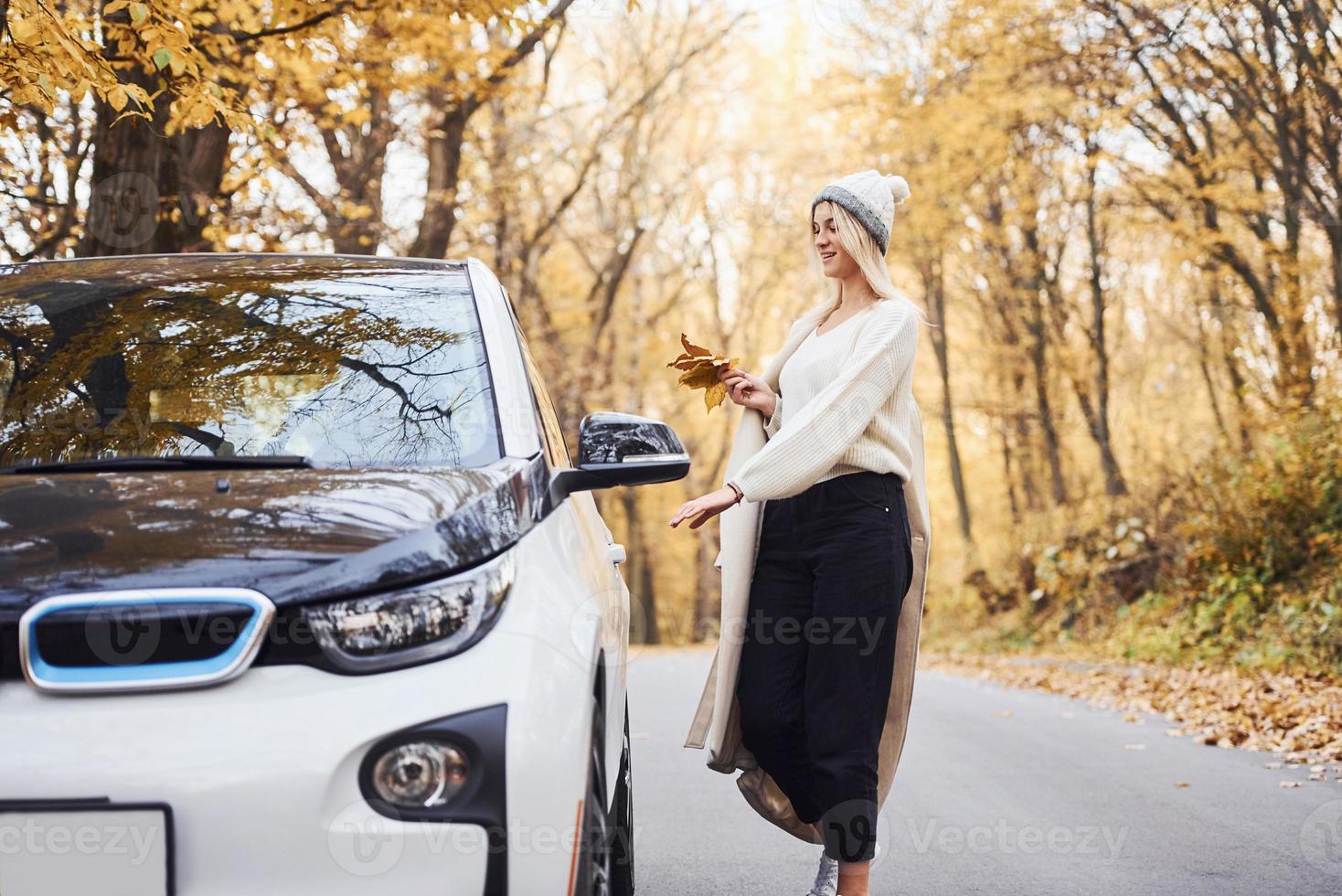 Enjoying nature. Girl have autumn trip by car. Modern brand new automobile in the forest photo