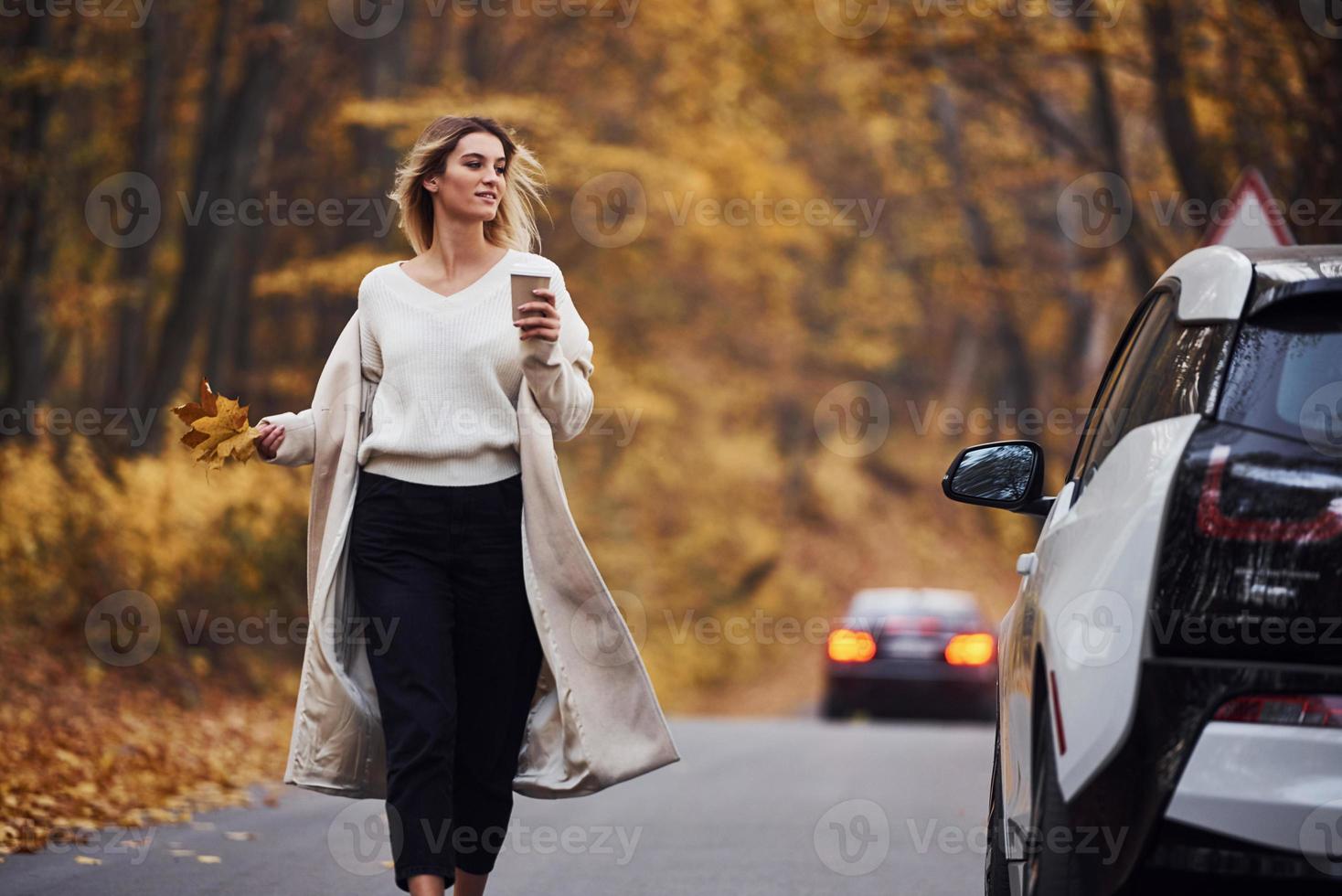 disfrutando de la naturaleza. chica tiene viaje de otoño en coche. automóvil nuevo y moderno en el bosque foto