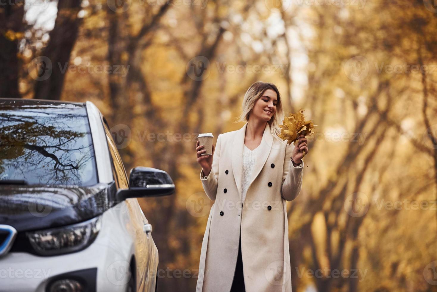 Enjoying nature. Girl have autumn trip by car. Modern brand new automobile in the forest photo