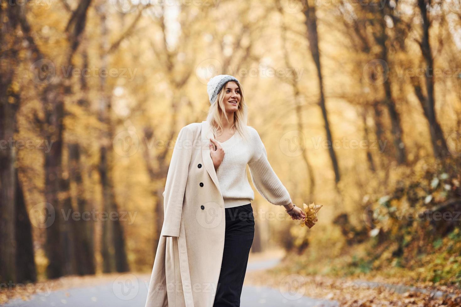 retrato de una joven morena que da un paseo por la carretera en el bosque de otoño durante el día foto