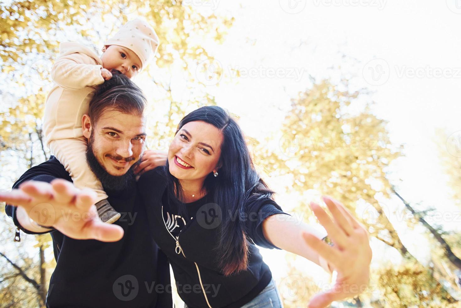 familia alegre divirtiéndose junto con su hijo en el hermoso parque de otoño foto