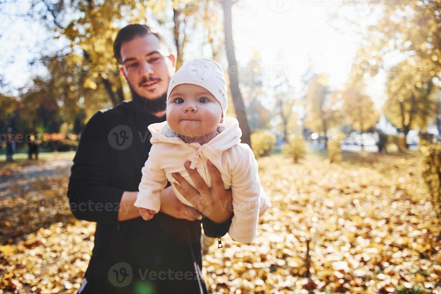 agradable luz del sol. padre con ropa informal con su hijo está en el hermoso parque de otoño foto
