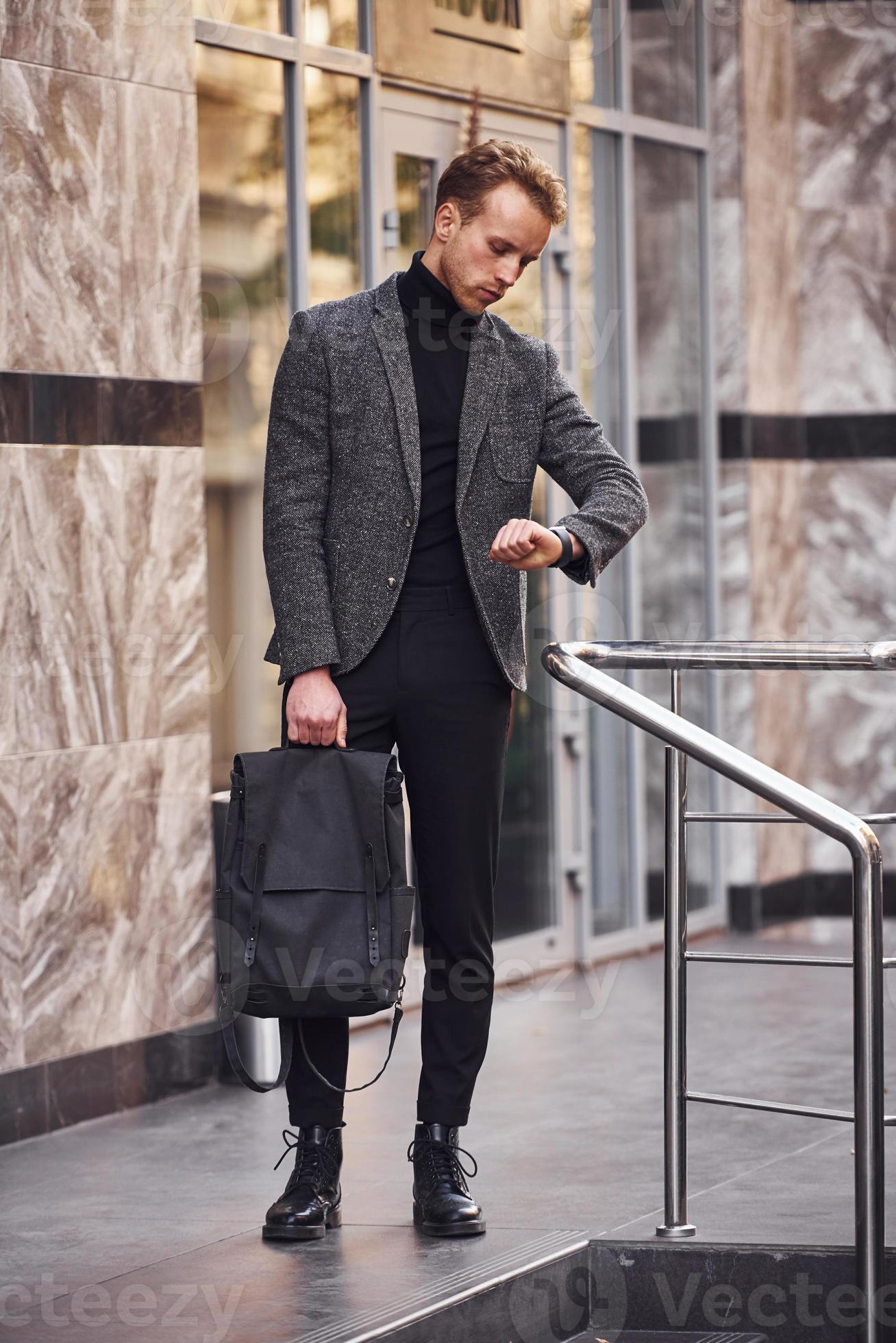 Hombre con elegante ropa formal y con bolsa está fuera contra el edificio  moderno Fotografía de stock - Alamy