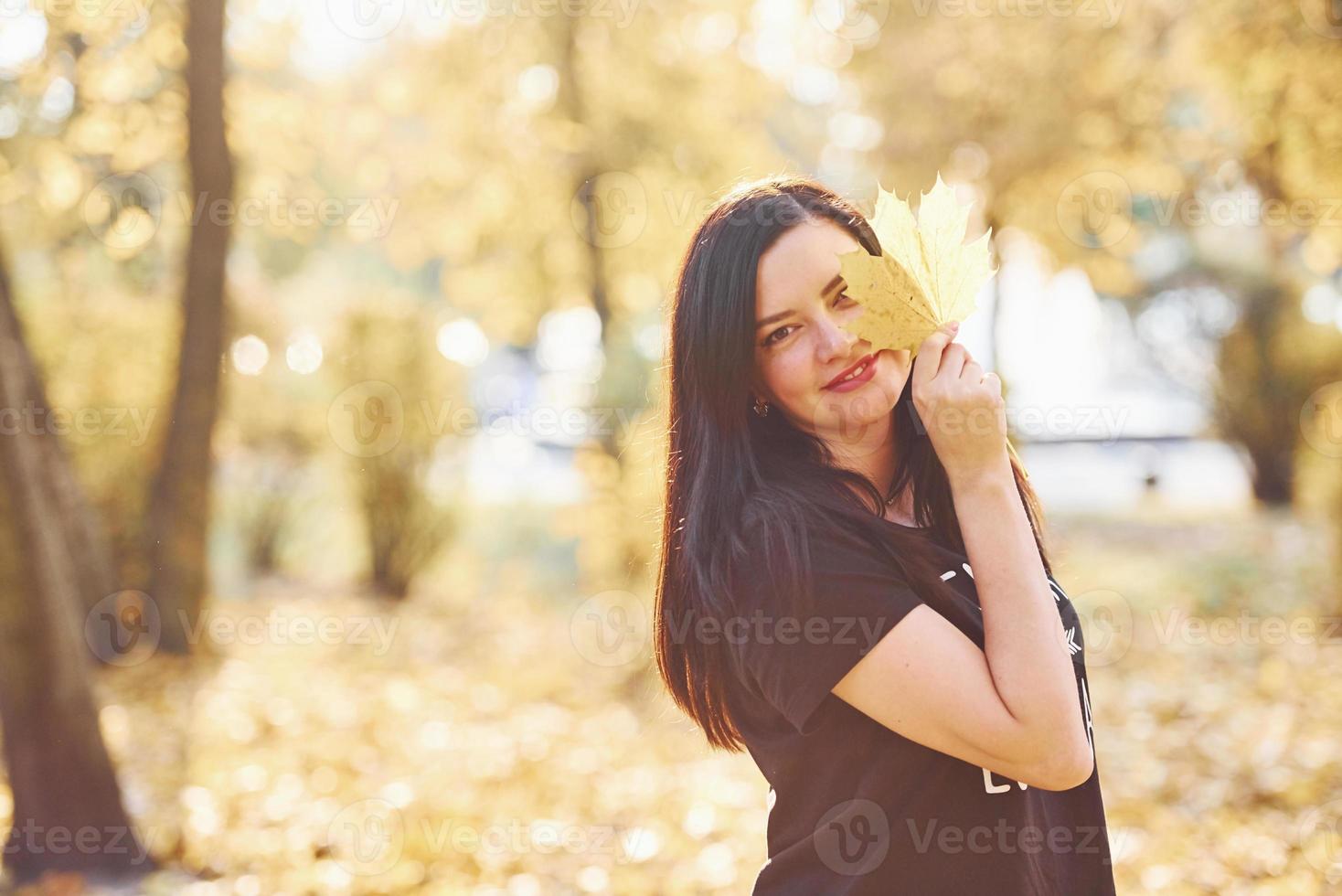 Portrait of brunette that have fun with leaves in beautiful autumn park photo