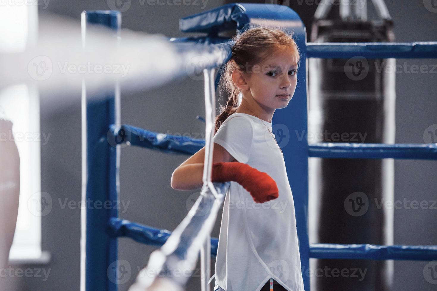 On the boxing ring. Young little girl in sportive wear is in the gym have exercise day photo