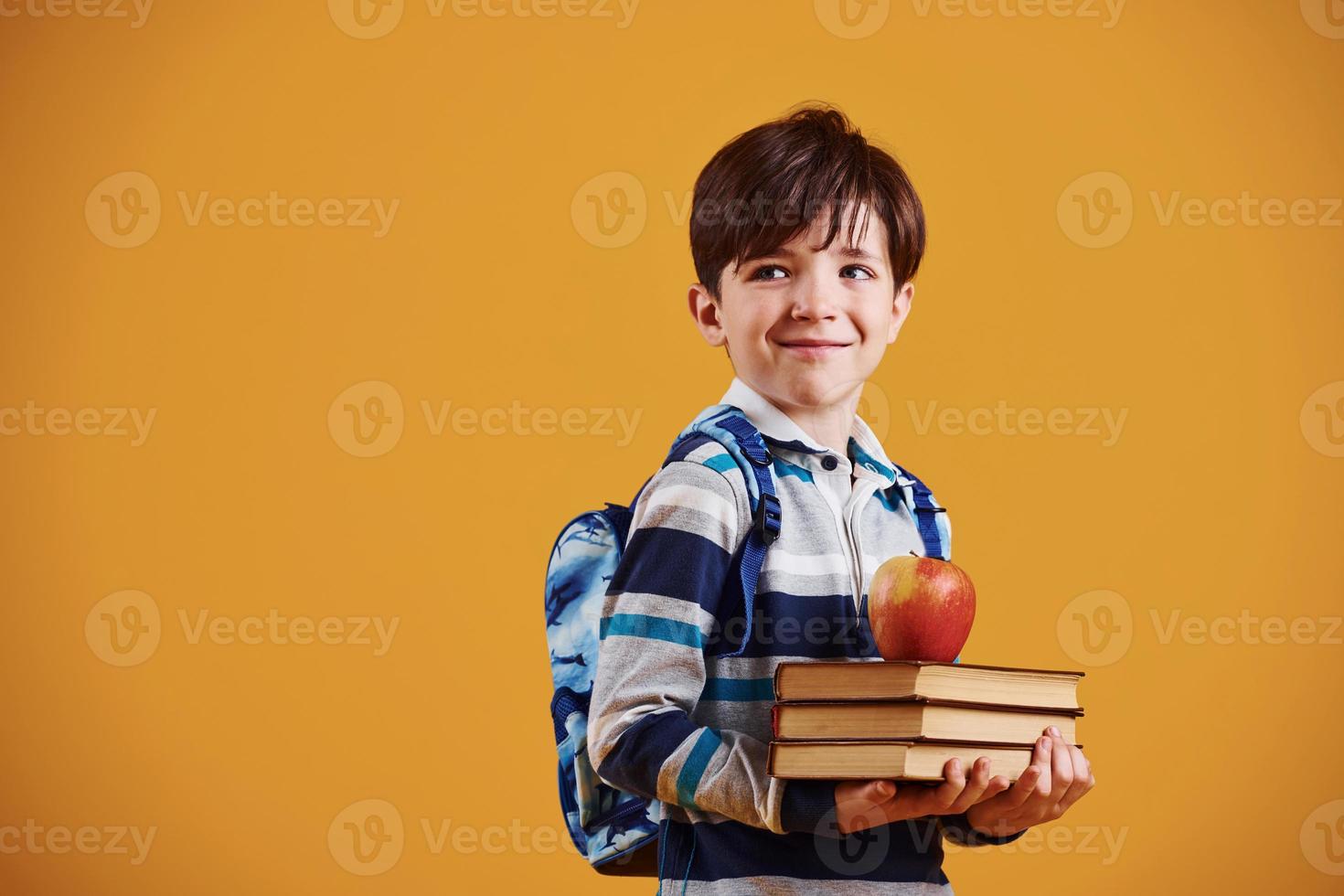 Portrait of young smart schooler in the studio against yellow background photo