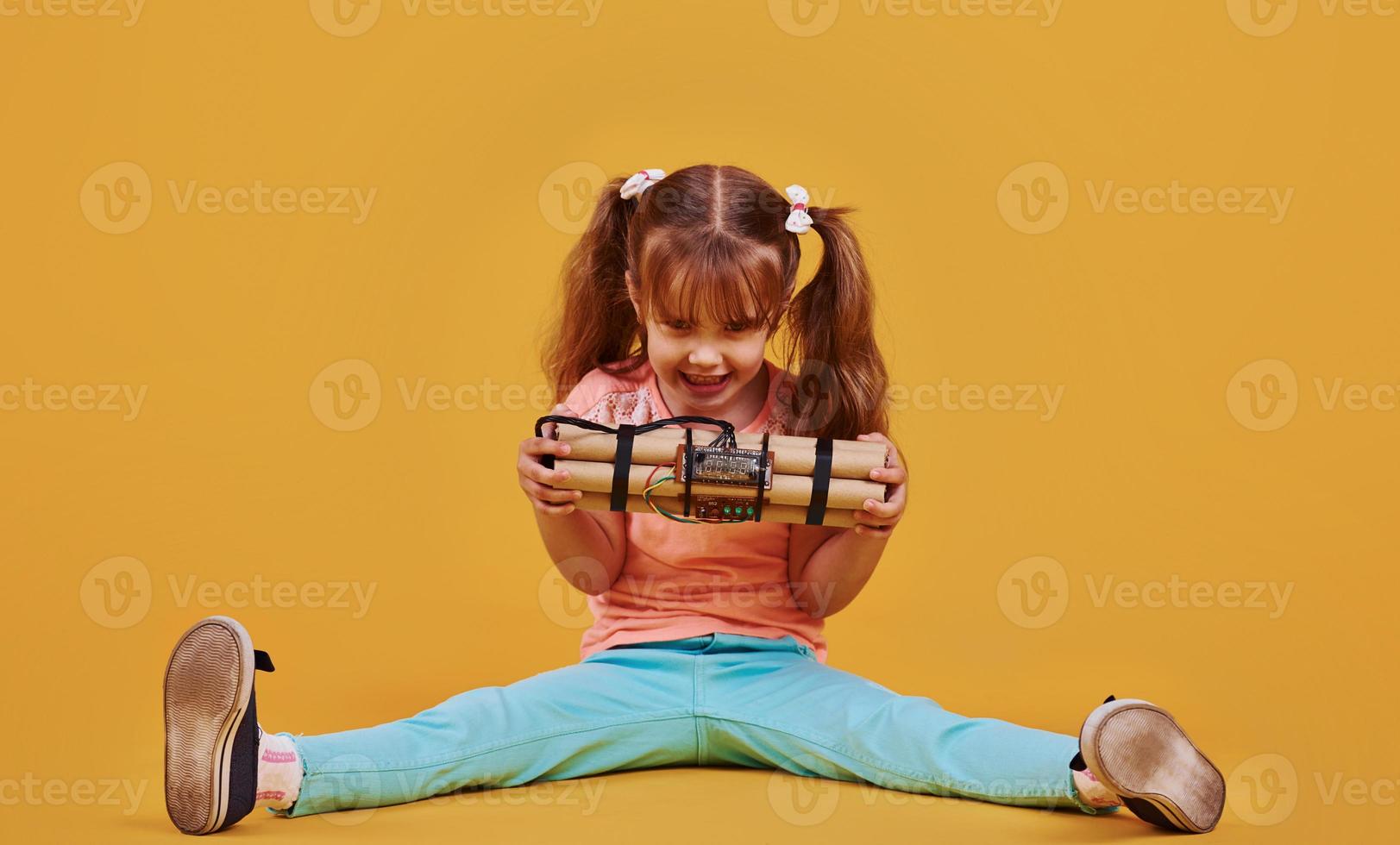 niñita con explosivo en el estudio con fondo amarillo foto