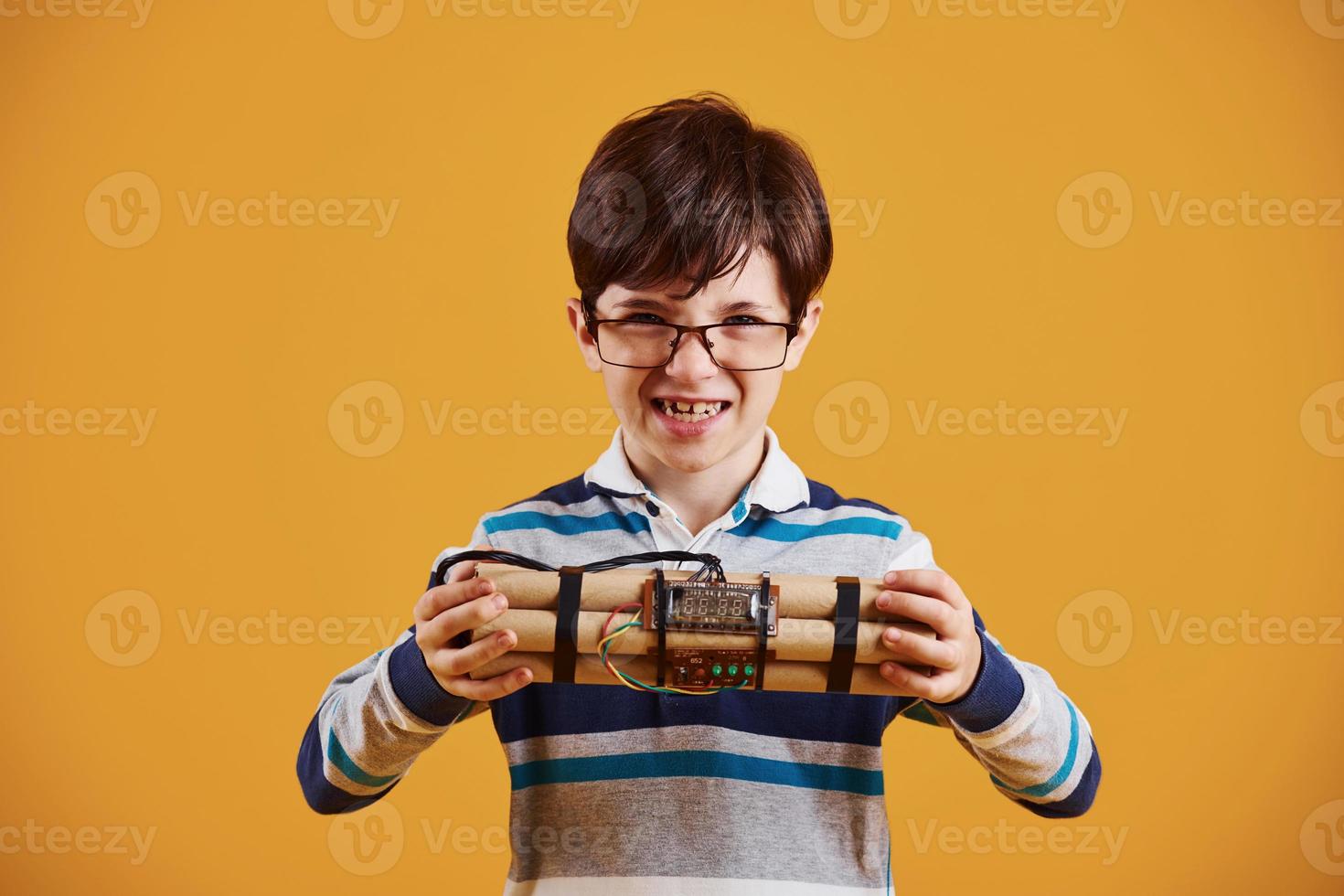 niño pequeño con explosivo en el estudio con fondo amarillo foto