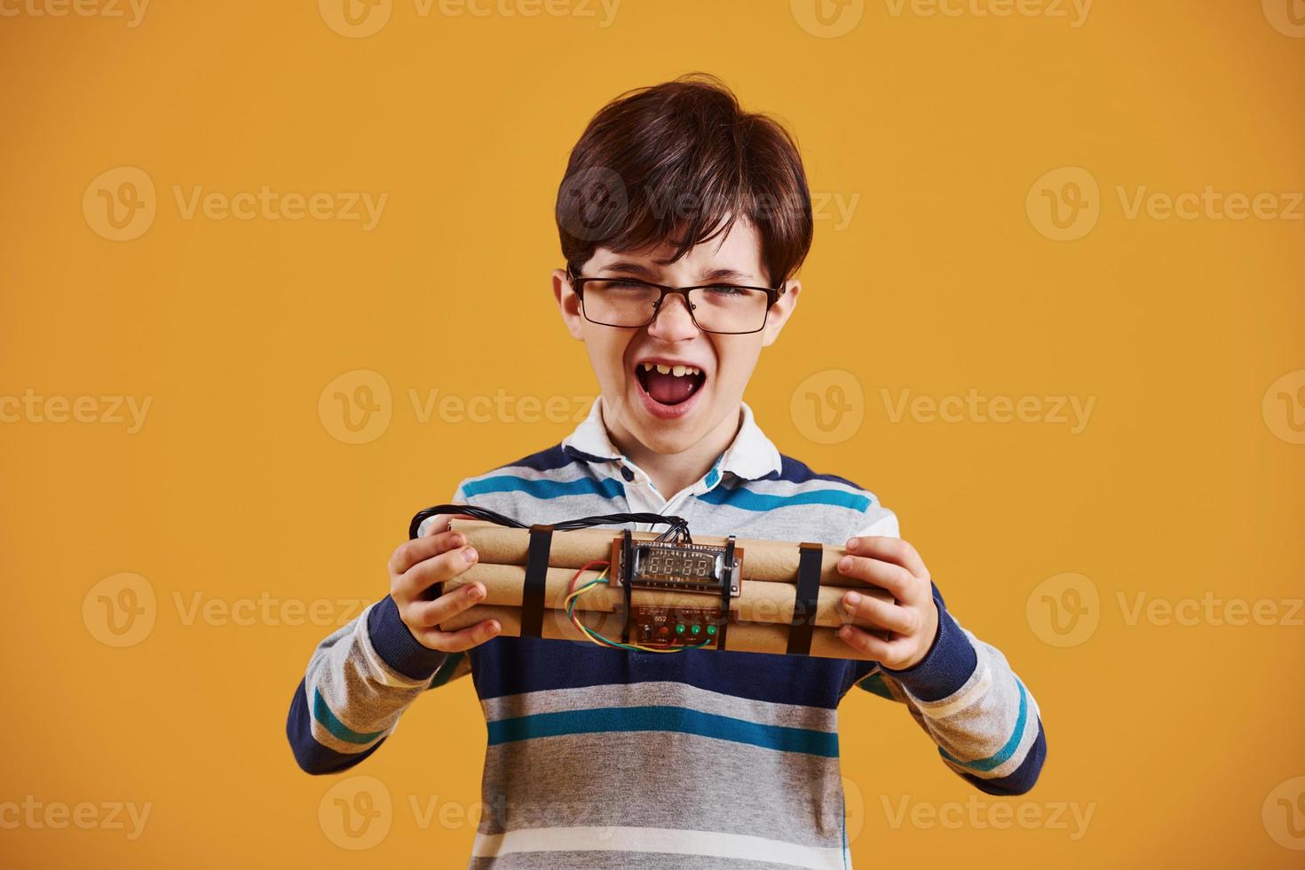 niño pequeño con explosivo en el estudio con fondo amarillo foto