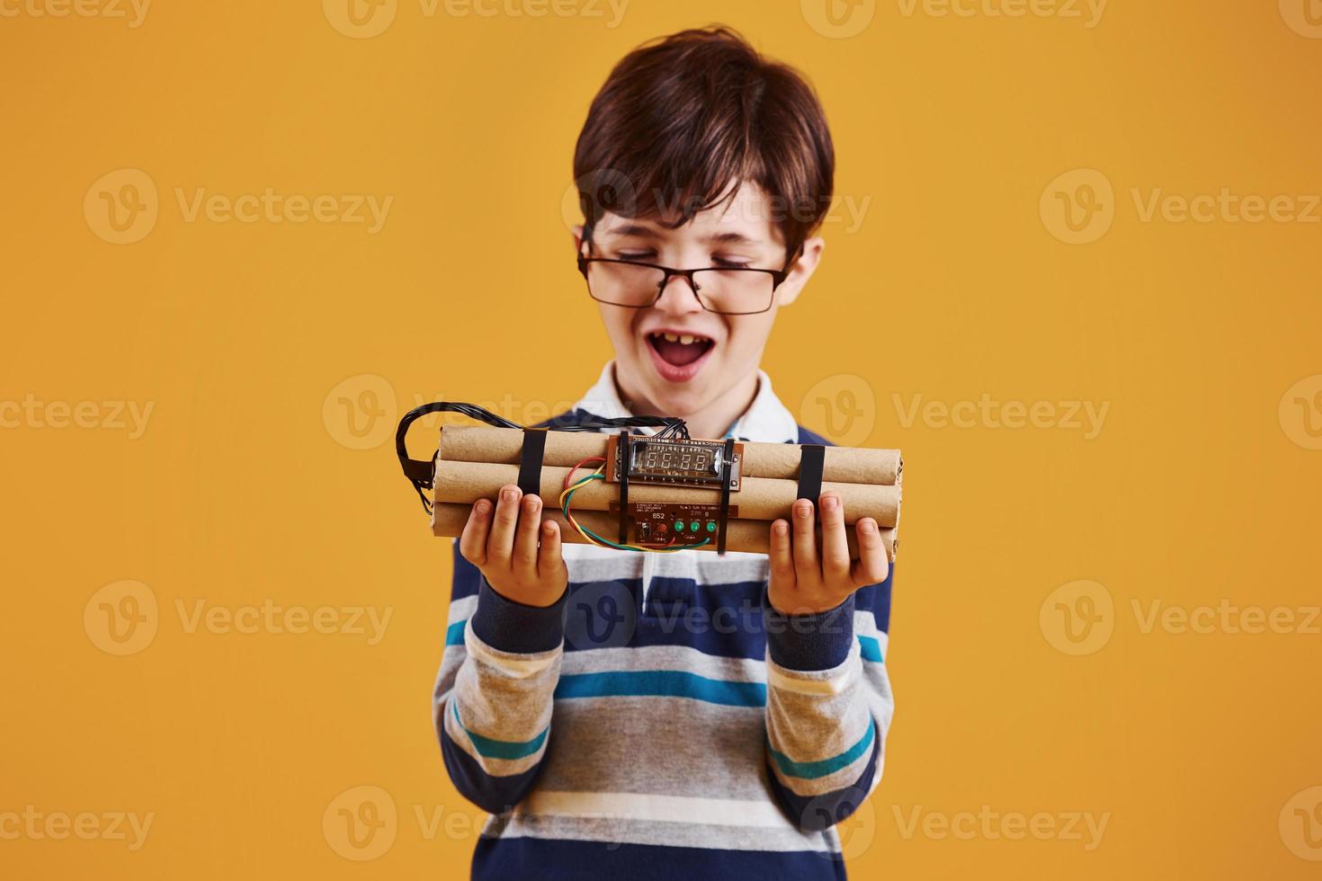 niño pequeño con explosivo en el estudio con fondo amarillo foto