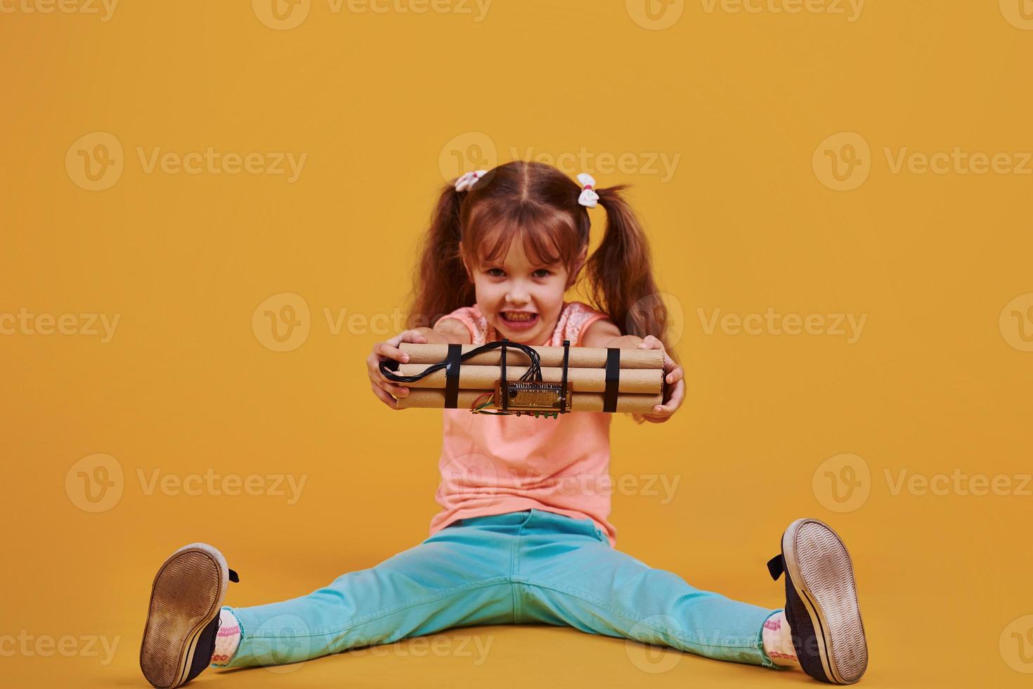 niñita con explosivo en el estudio con fondo amarillo foto