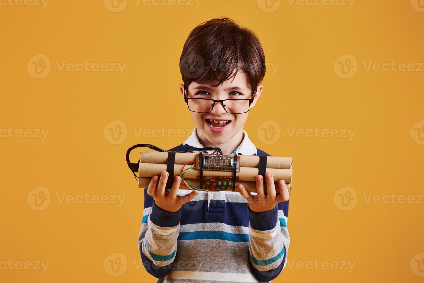 niño pequeño con explosivo en el estudio con fondo amarillo foto