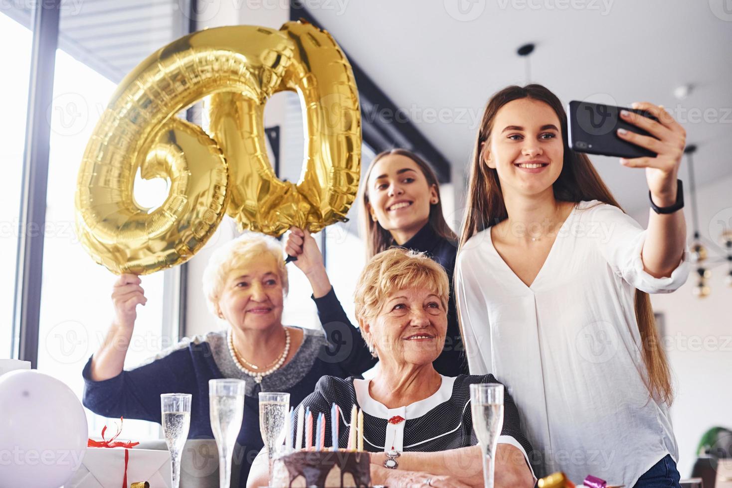 globos con el número 60. mujer mayor con familiares y amigos celebrando un cumpleaños en el interior foto