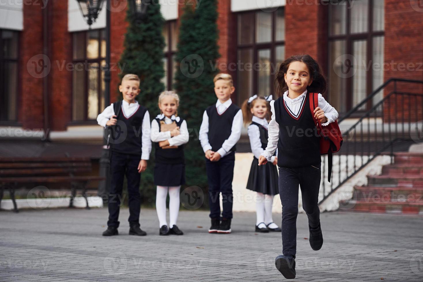 grupo de niños con uniforme escolar posando juntos para la cámara al aire libre cerca del edificio educativo foto