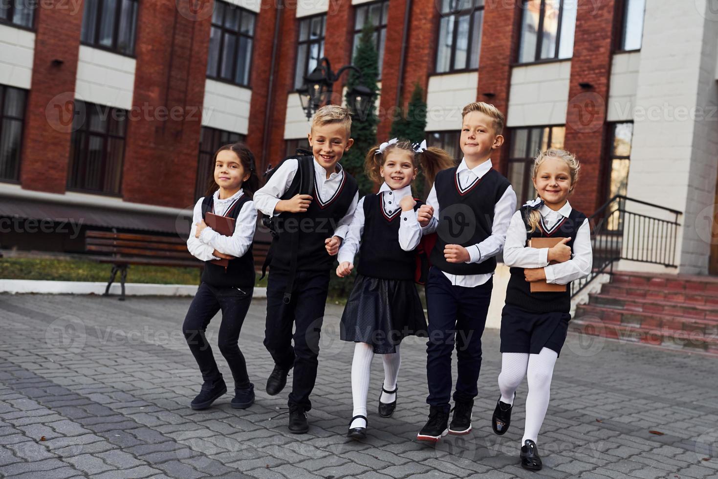 grupo de niños con uniforme escolar posando juntos para la cámara al aire libre cerca del edificio educativo foto