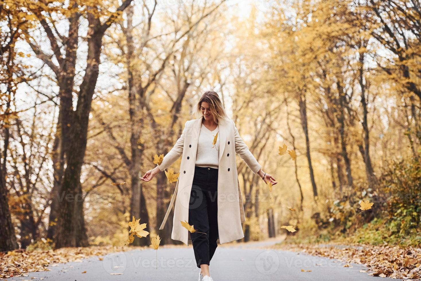 Having fun with leaves. Portrait of young brunette that is in autumn forest at daytime photo