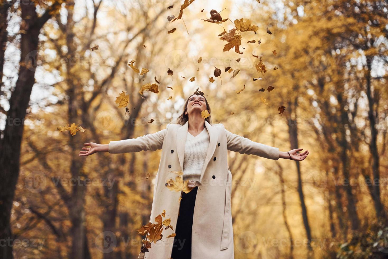 Having fun with leaves. Portrait of young brunette that is in autumn forest at daytime photo