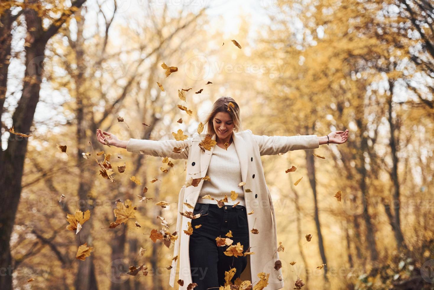 Having fun with leaves. Portrait of young brunette that is in autumn forest at daytime photo