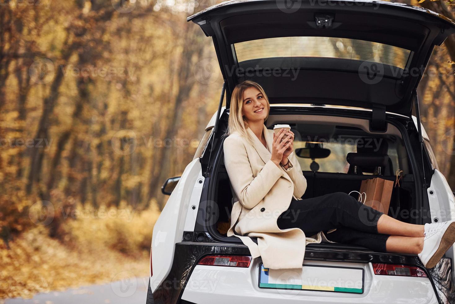 Girl sits on the back of car. Modern brand new automobile in the forest photo