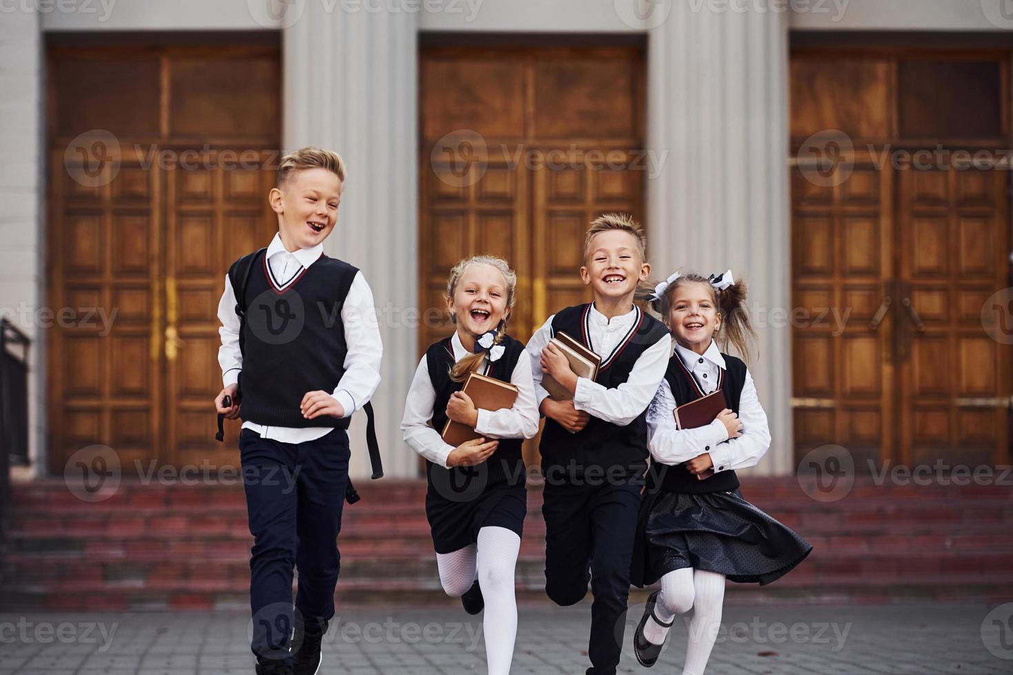 Group of kids in school uniform that is running outdoors together photo