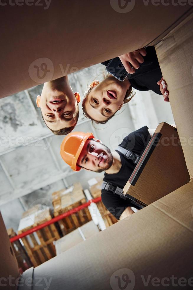 View from inside of paper box. Cheerful people looks down together photo