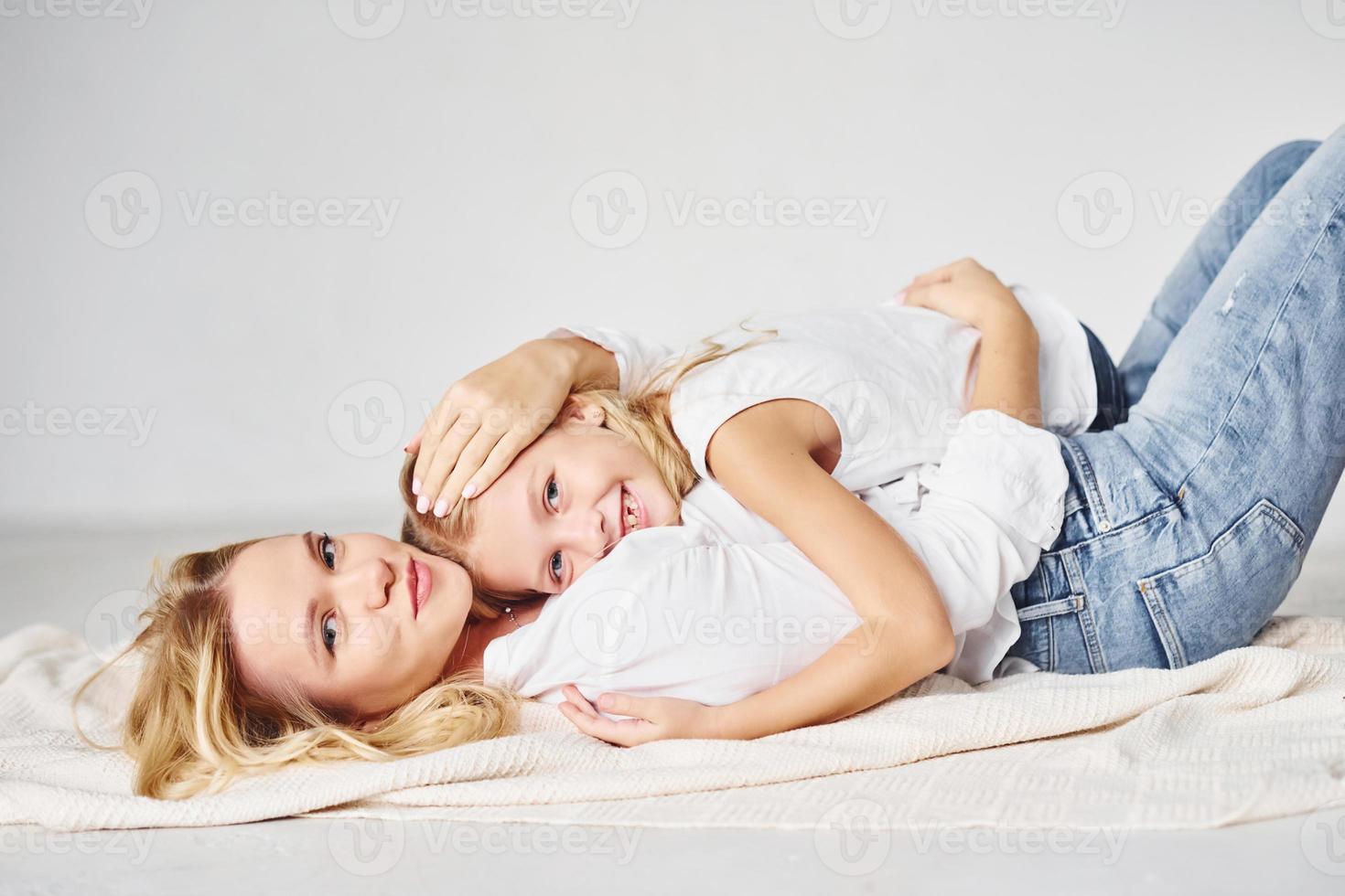 Mother with her daughter together is on the ground in the studio with white background photo