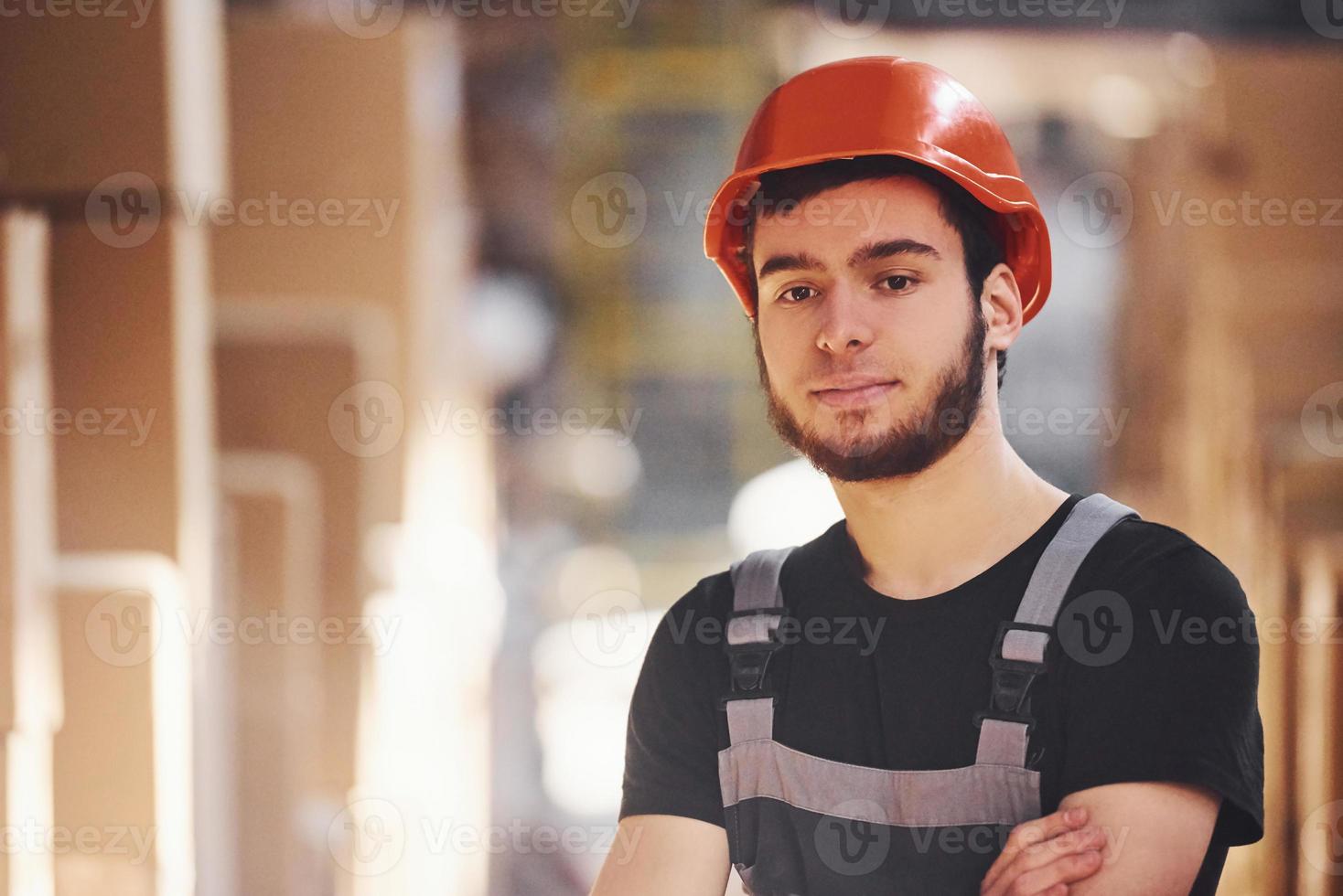 Portrait of young storage worker in warehouse in uniform and hard hat photo