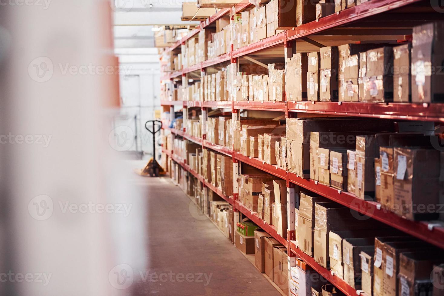 Storage room with pallet truck and many of objects at daytime photo