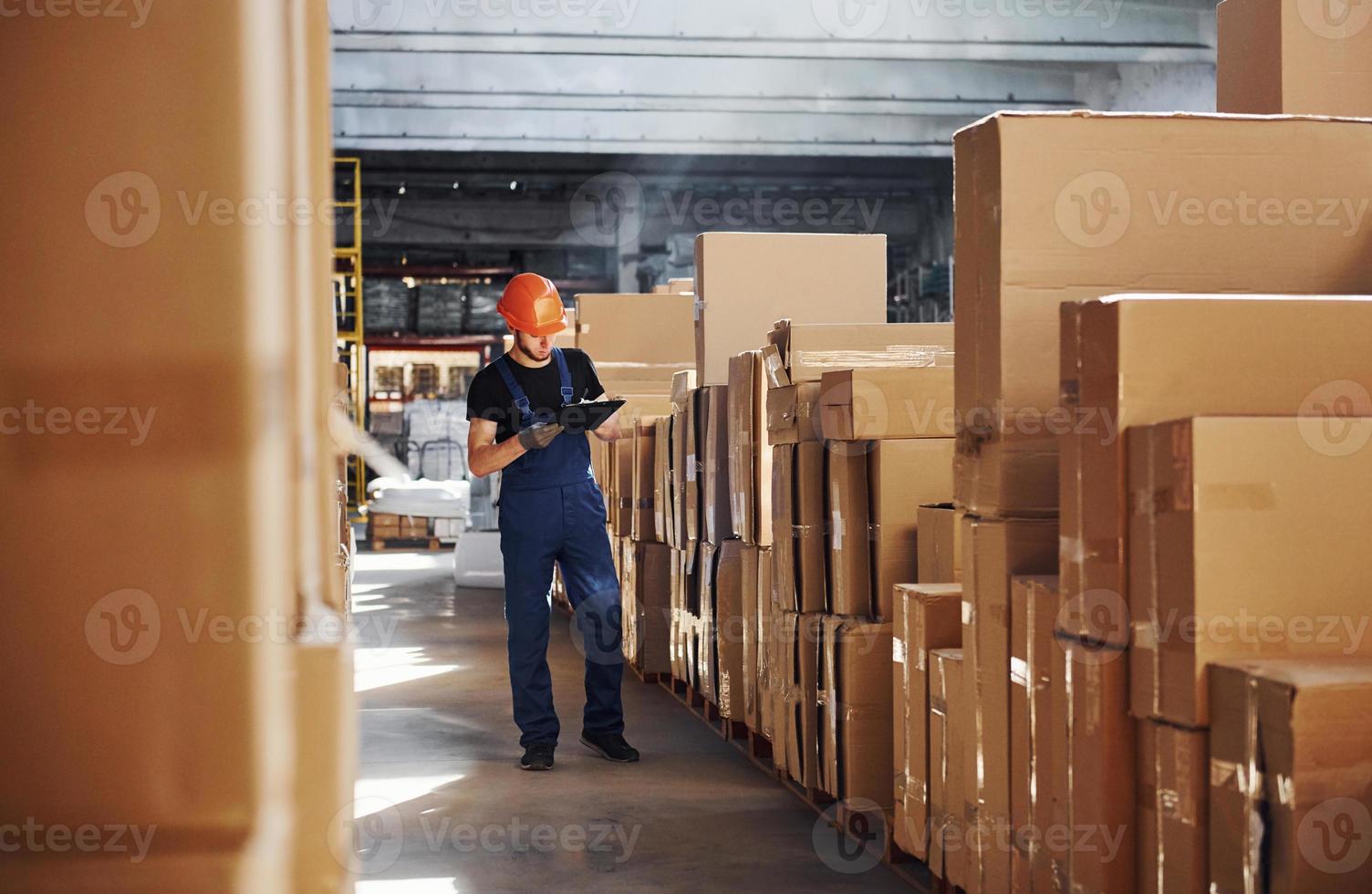 trabajador de almacenamiento en uniforme y bloc de notas en manos producción de cheques foto