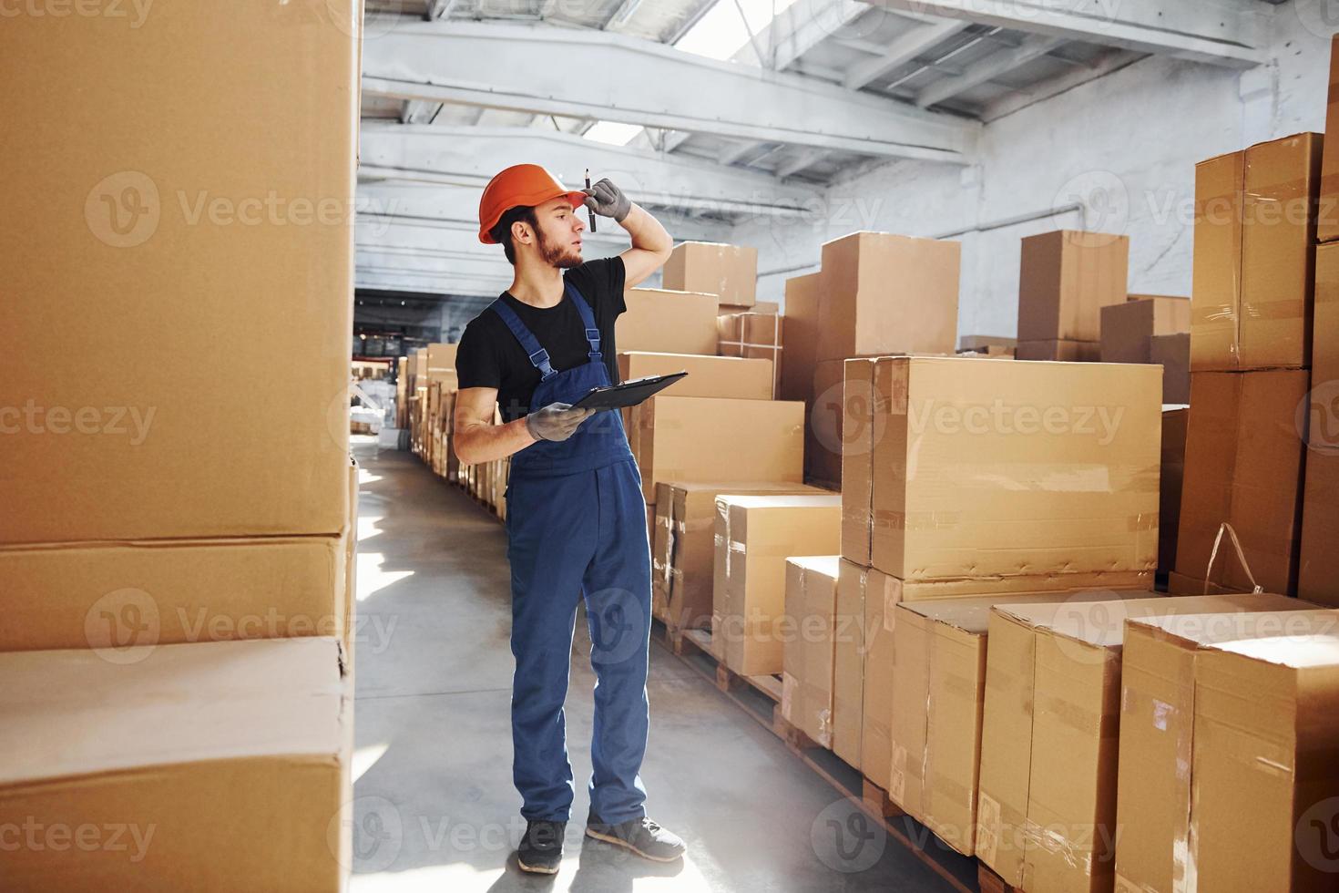 trabajador de almacenamiento en uniforme y bloc de notas en manos producción de cheques foto