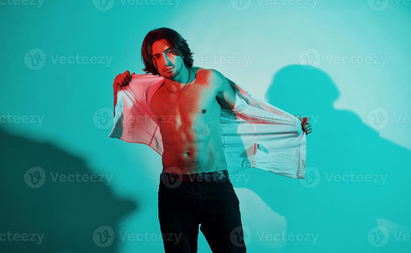 Portrait of young hot man that stands in neon lights in the studio photo