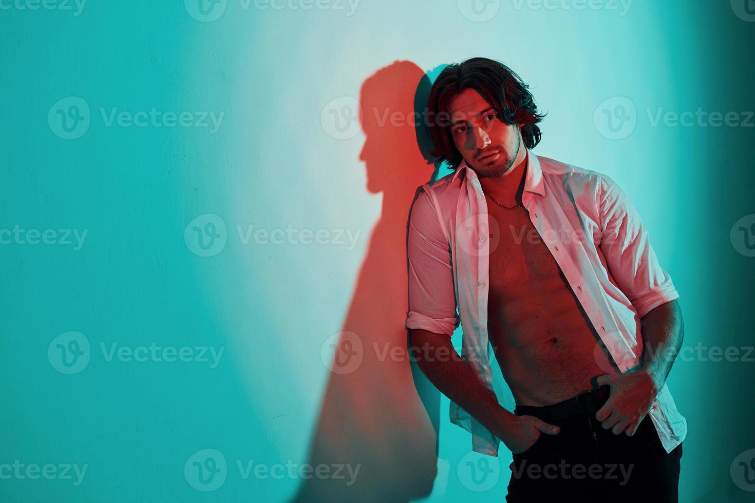 Portrait of young hot man that stands in neon lights in the studio photo