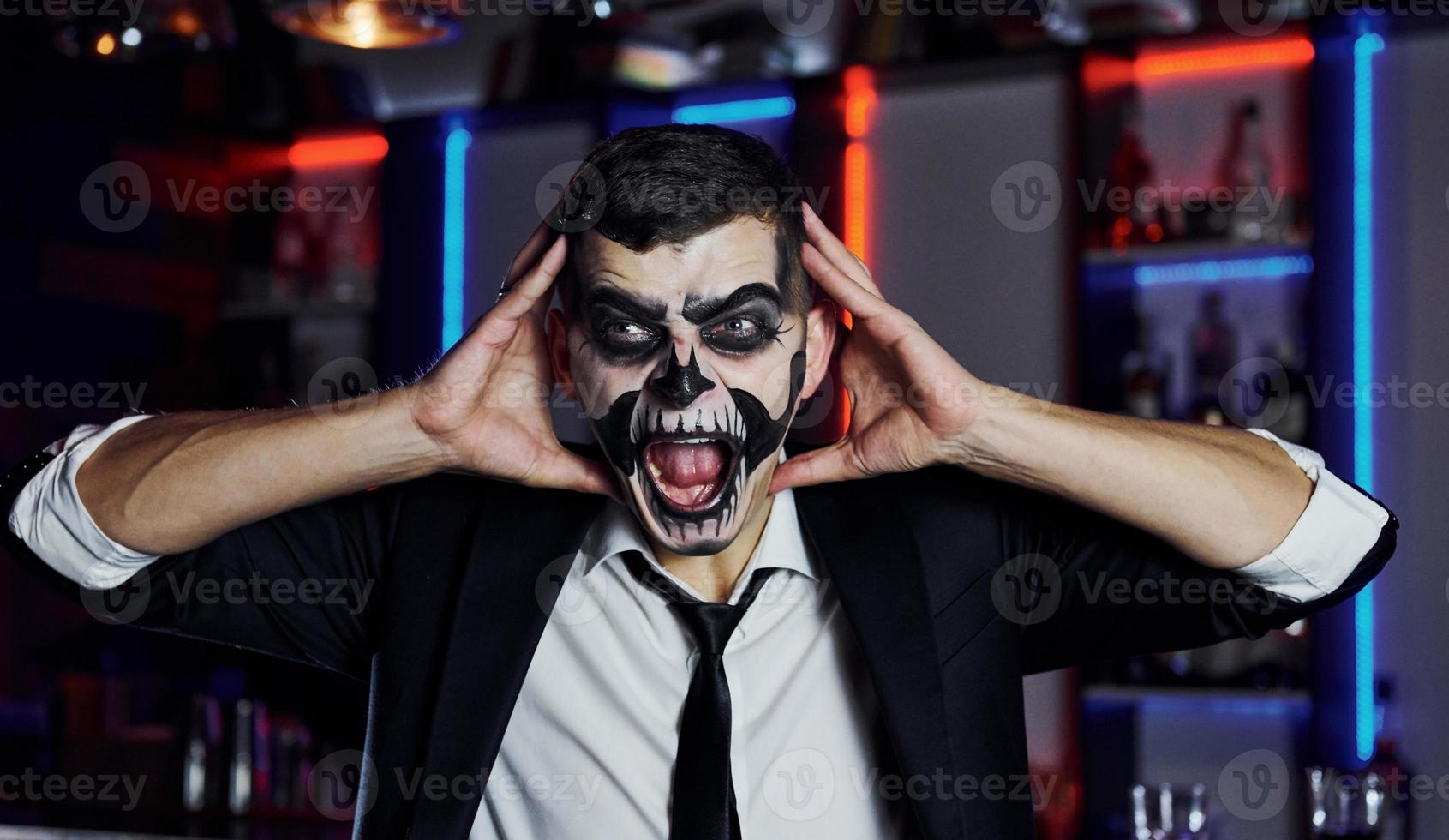 Portrait of man that is on the thematic halloween party in scary skeleton makeup and costume photo