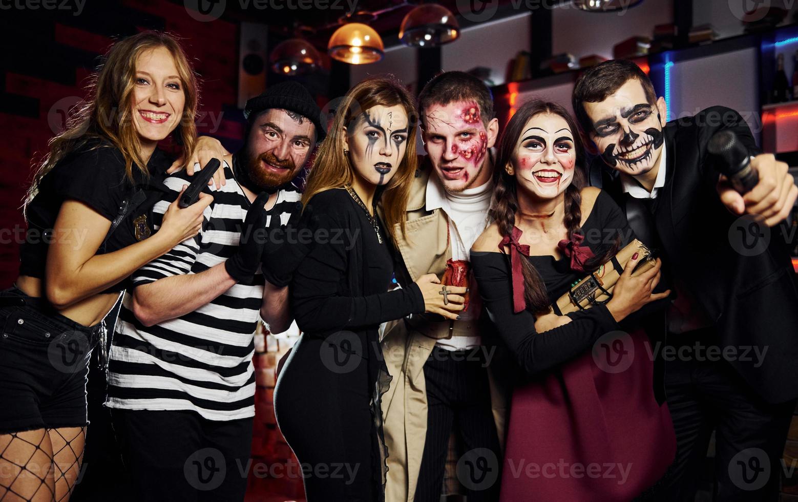 Friends is on the thematic halloween party in scary makeup and costumes have fun and posing for the camera together photo