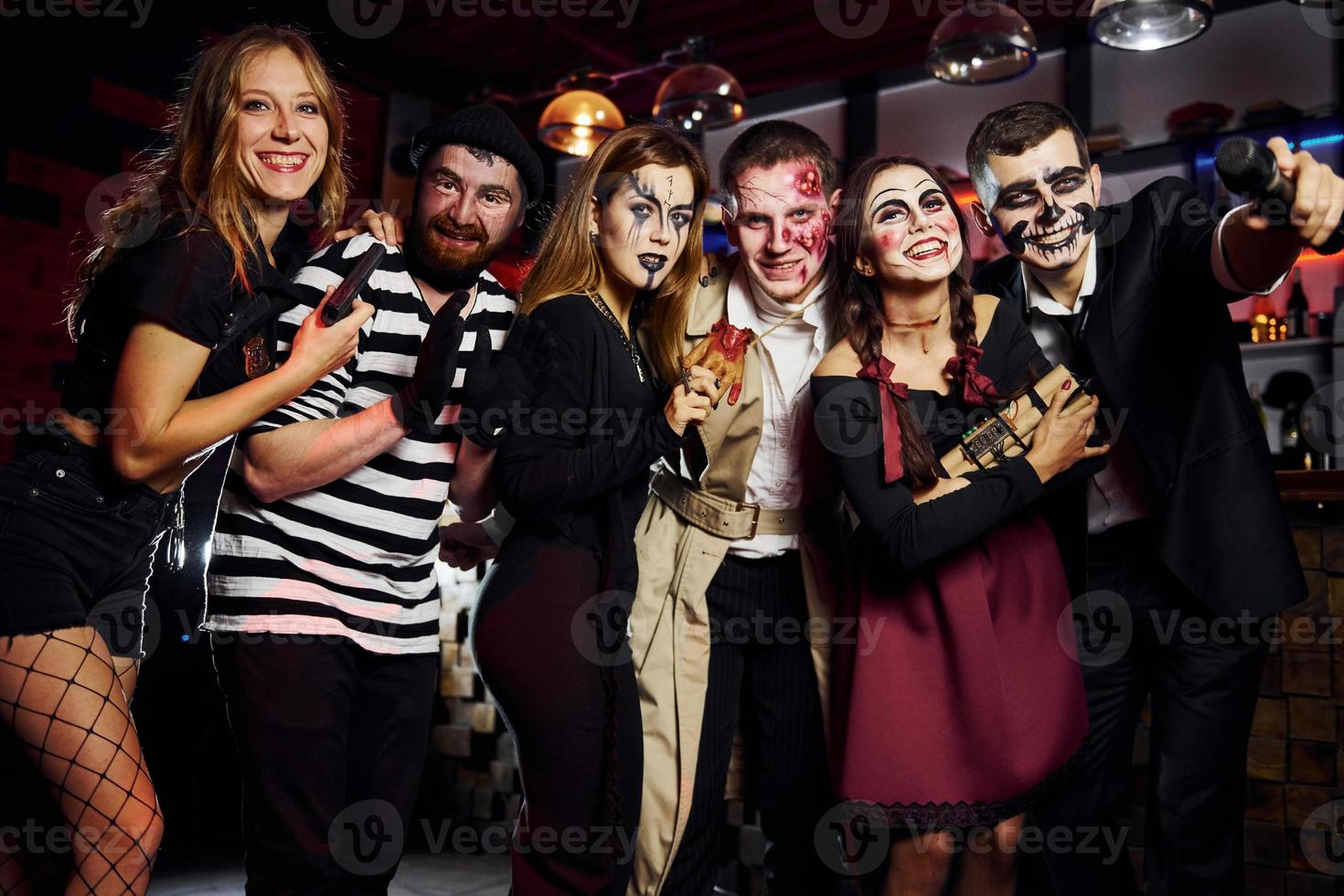 Friends is on the thematic halloween party in scary makeup and costumes have fun and posing for the camera together photo