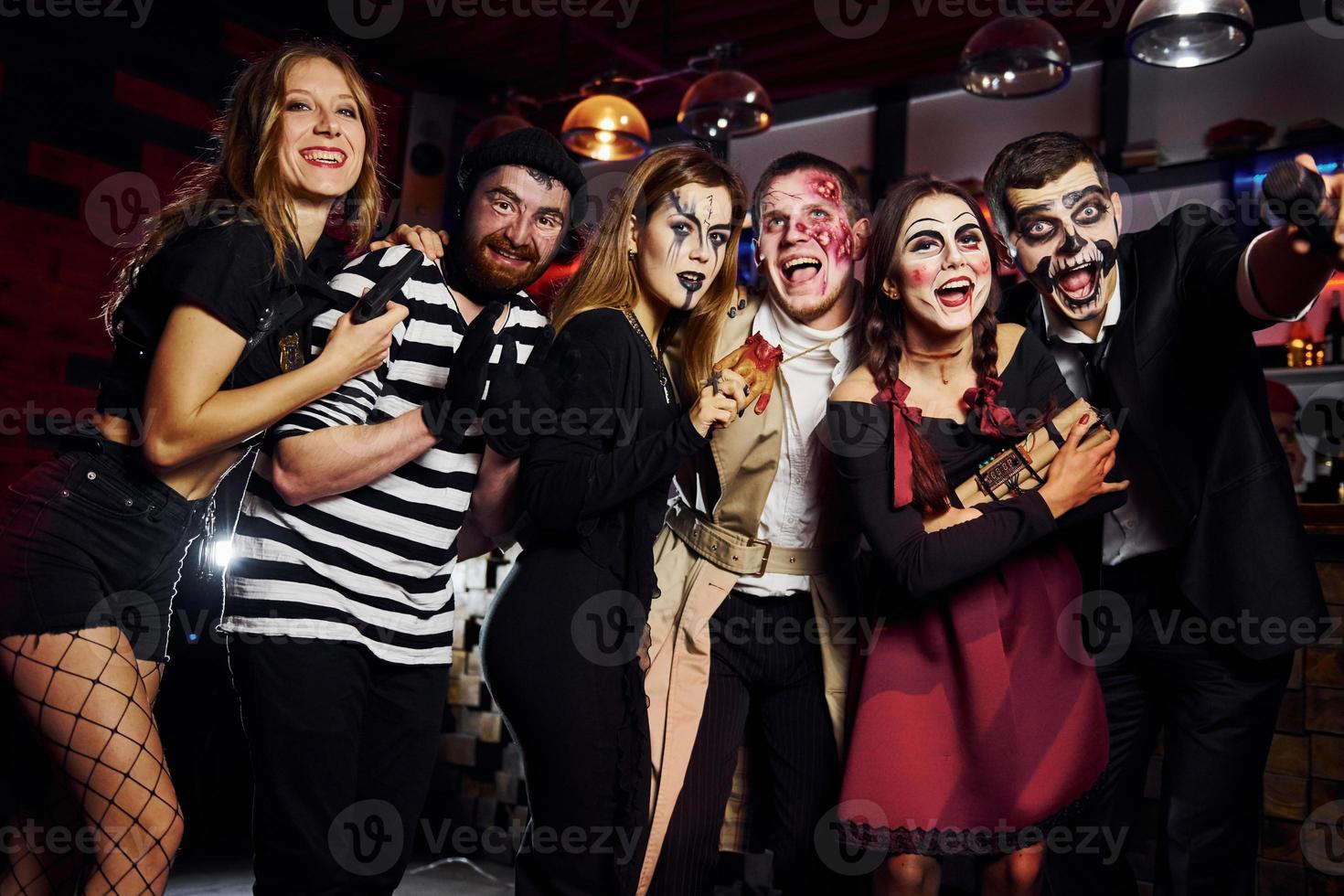 Friends is on the thematic halloween party in scary makeup and costumes have fun and posing for the camera together photo